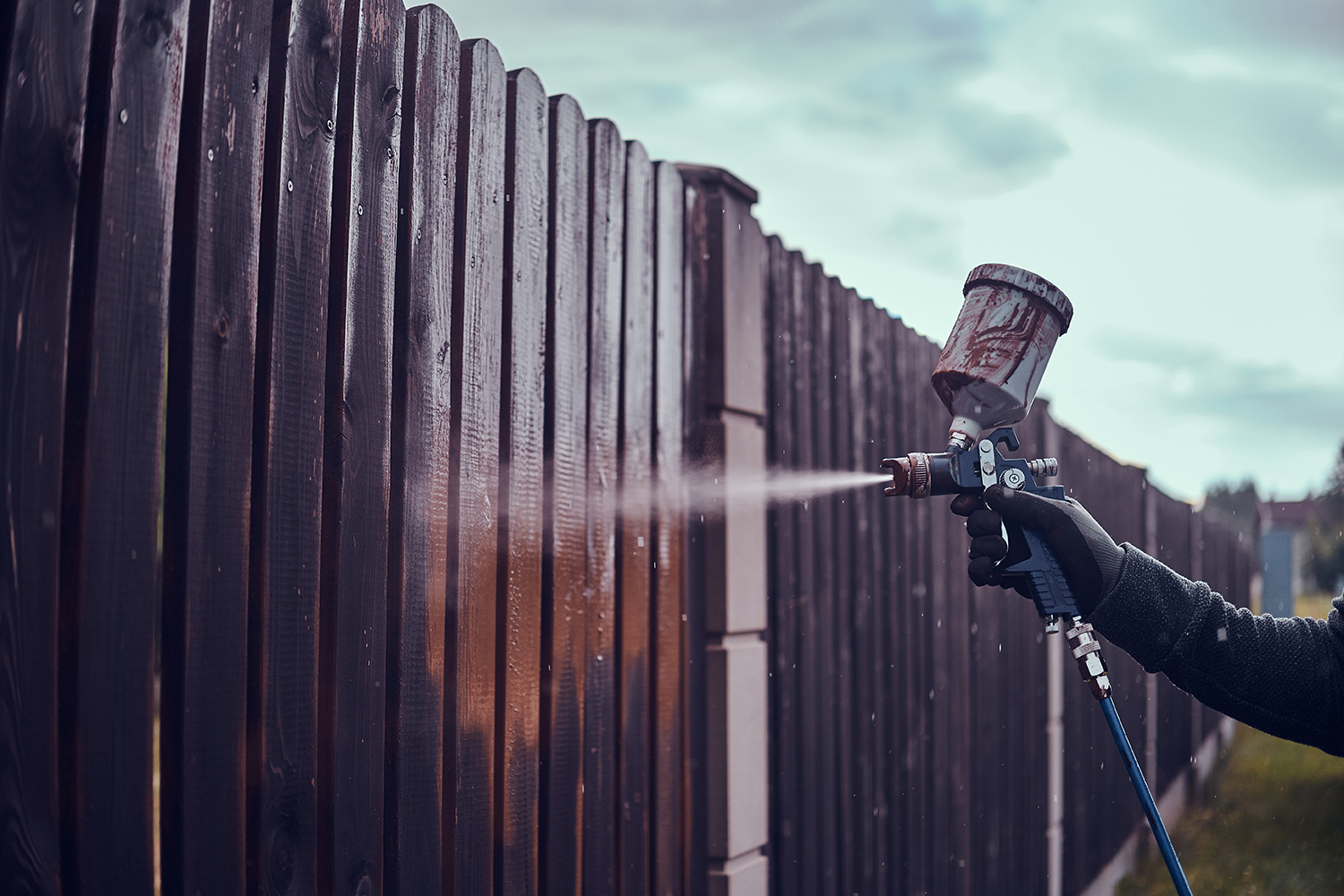 Diligent working is applying colour to the fence with airbrush